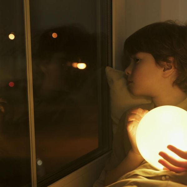 Person meditating peacefully in a room with soft light.