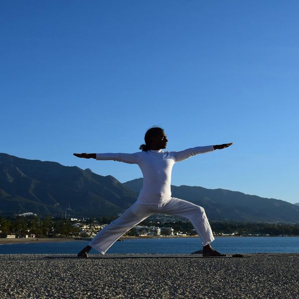 Silhouette of a person in a powerful yoga warrior pose at sunrise.